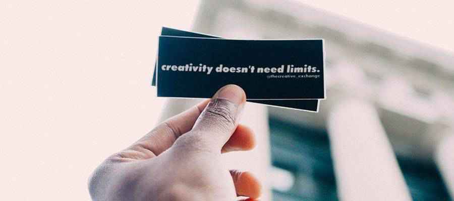 Person holding a sticker that reads "creativity doesn't need limits".