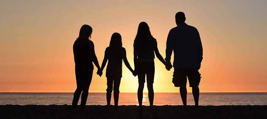 A family holding hands on the beach.