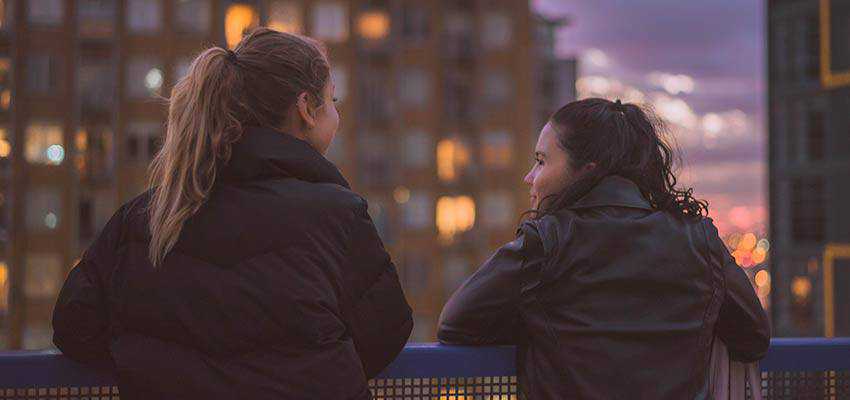 Two women outside, overlooking a city.