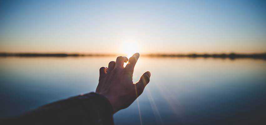 A hand reaching towards the sun.