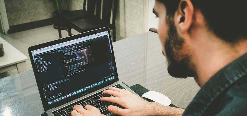 Man writing code on a laptop.