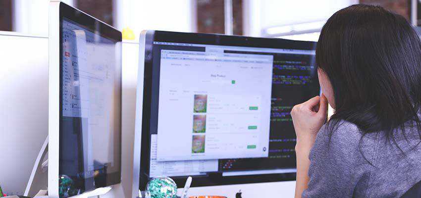 A woman using a dual monitor computer.